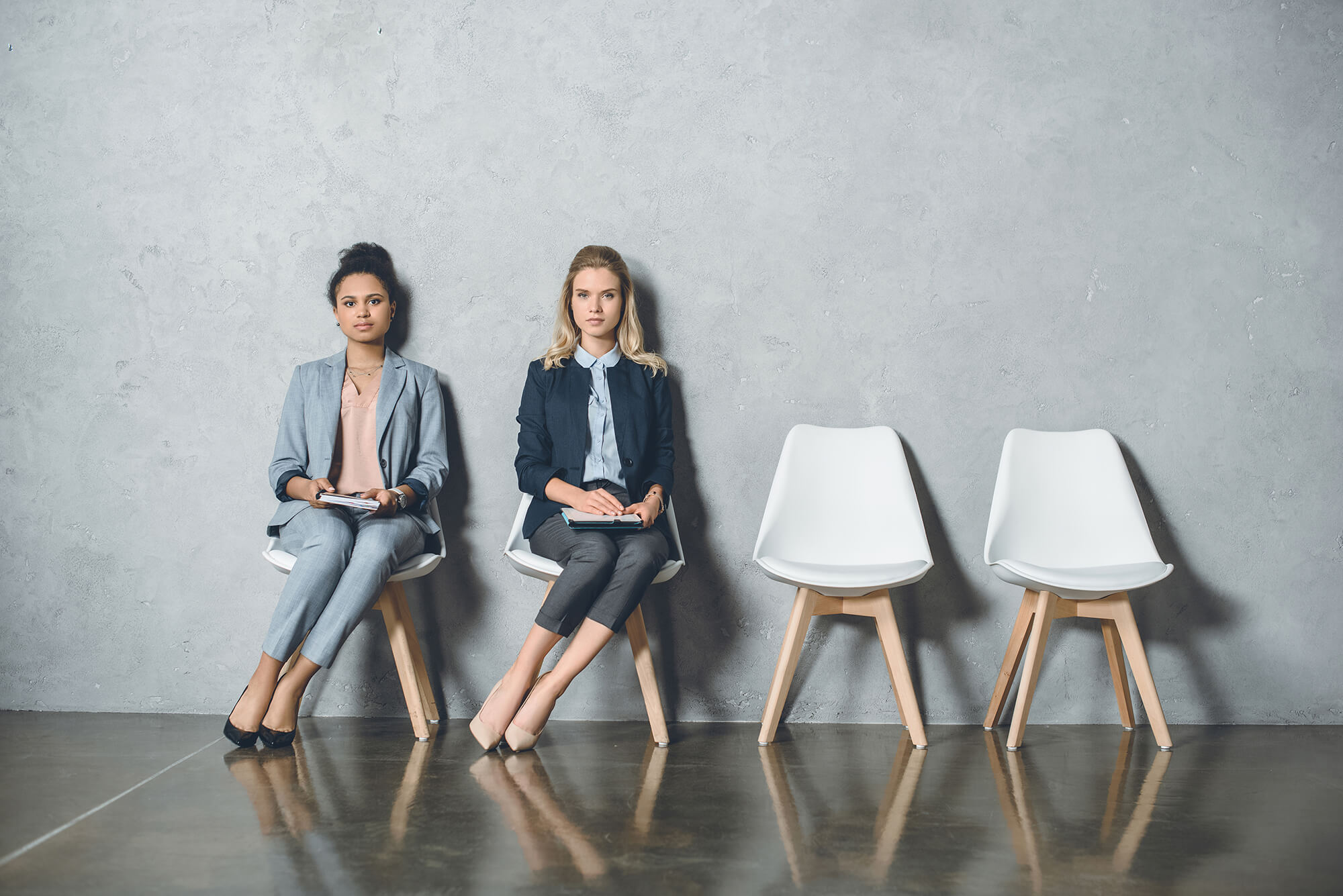 Two women sitting on a two chair waiting for something
