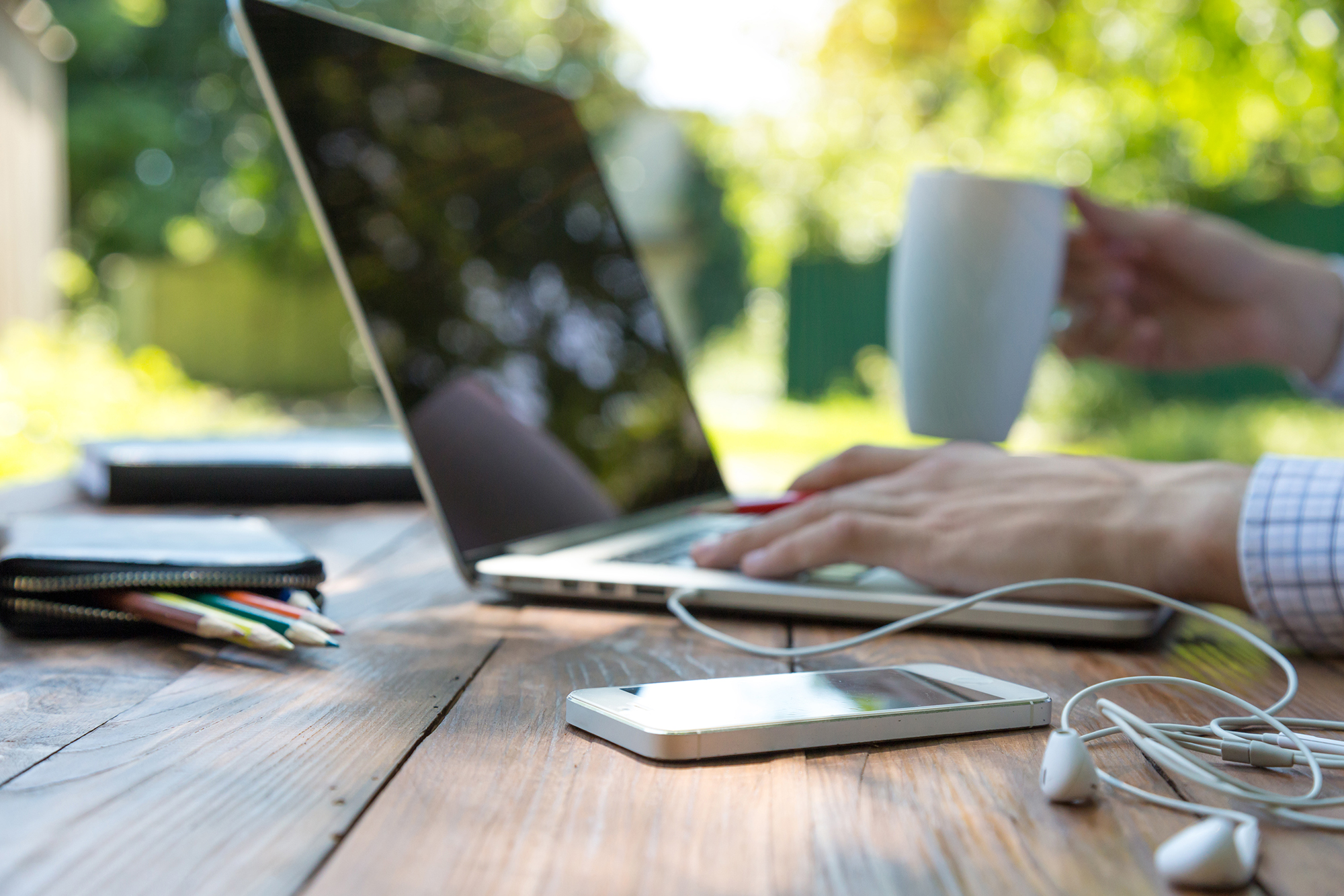 phone and laptop with man drinking coffee from mug