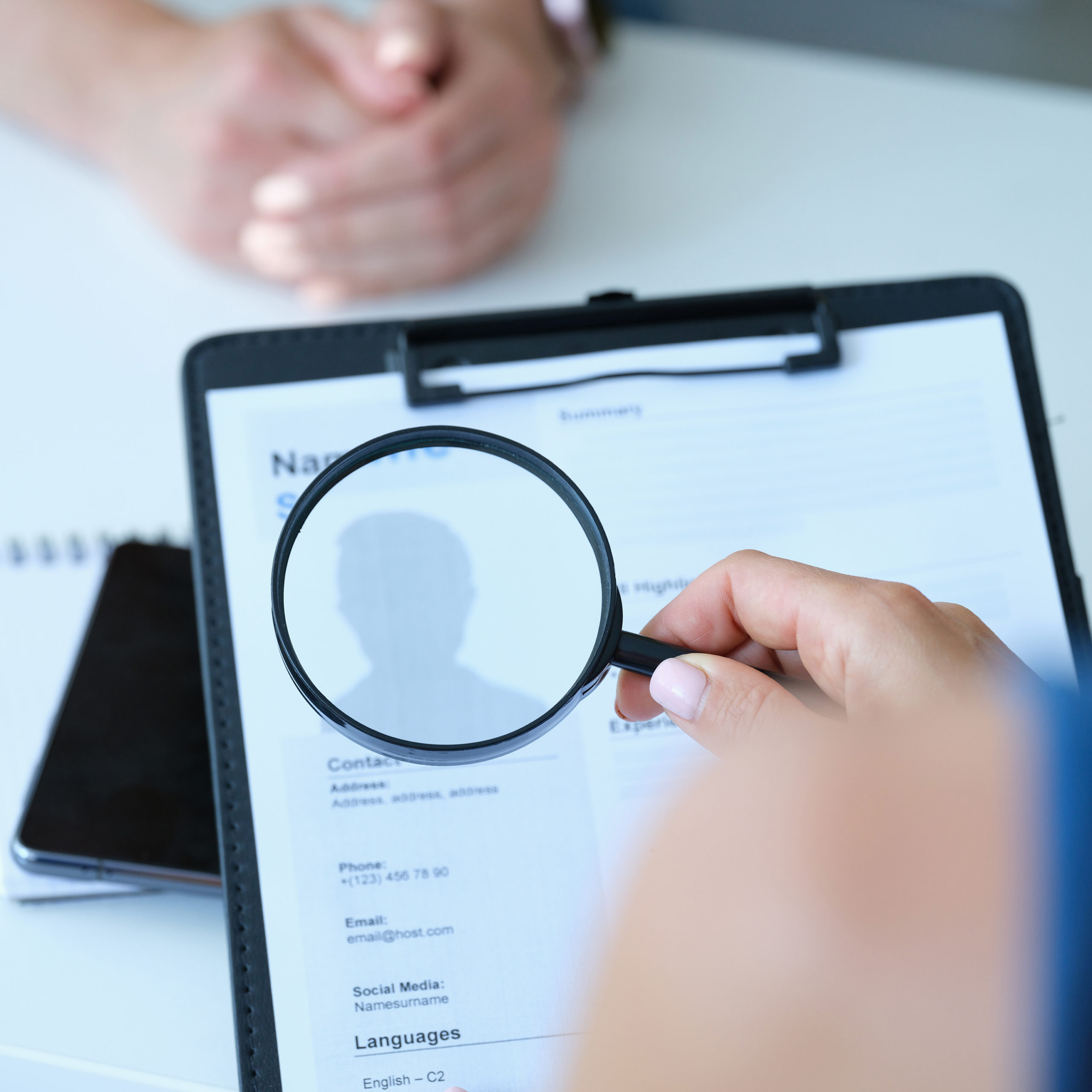 Employee examines resume application form under magnifying glass man headshot